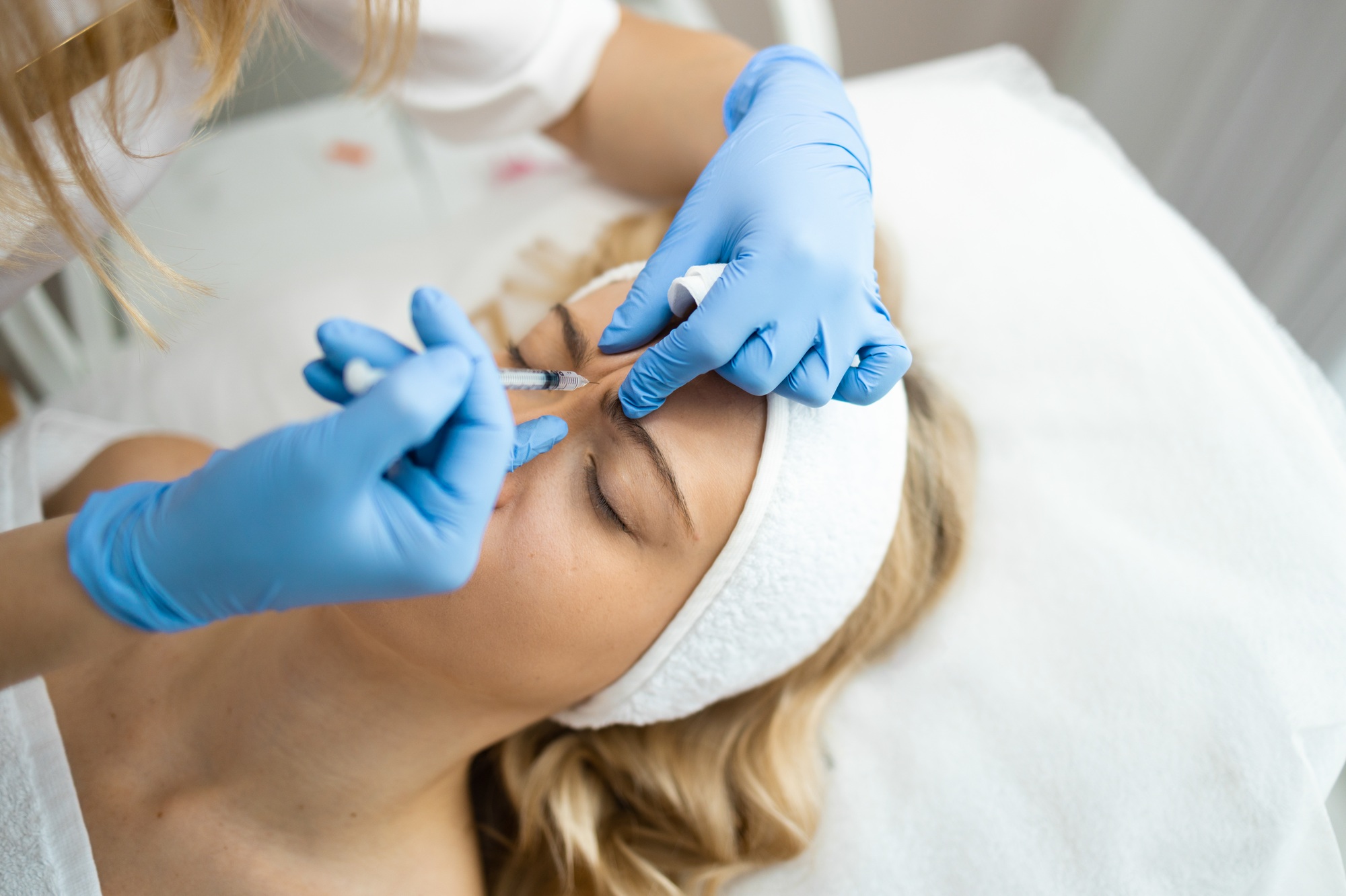 Cosmetologist makes rejuvenating anti wrinkle injections on the face of a beautiful woman.