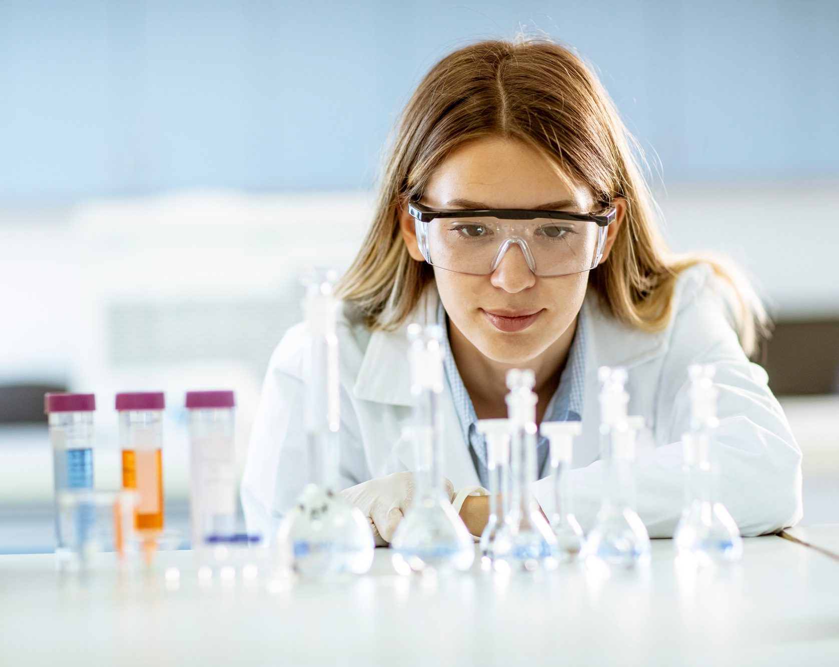 Female medical or scientific researcher looking at a flasks with solutions in a laboratory