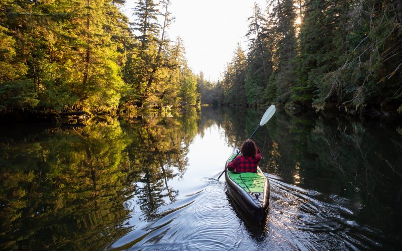 Girl kayaking in the river during a sunny summer morning